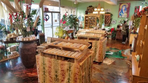 A cozy shop interior with wooden displays of soap, plants, and festive decorations, featuring a warm, inviting atmosphere.