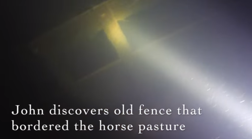 A dimly lit underwater scene showing an old fence, with text about John discovering it near a horse pasture.