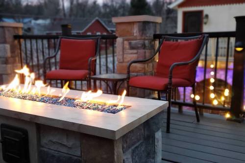 Cozy outdoor seating with two red chairs by a fire table, surrounded by a stone railing and soft evening lighting.