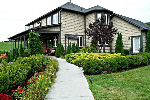 A charming house with a landscaped garden, featuring a curved pathway and vibrant flowers in front.