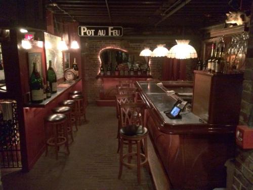 Cozy bar interior with wooden stools, a polished counter, and vintage lamps, creating a warm, inviting atmosphere.