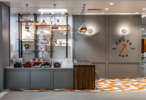 Modern BBQ restaurant interior featuring a stylish counter, shelves with decor, and a logo on the wall.