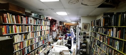 A cozy bookstore aisle lined with shelves of books, with customers browsing and exploring the space.