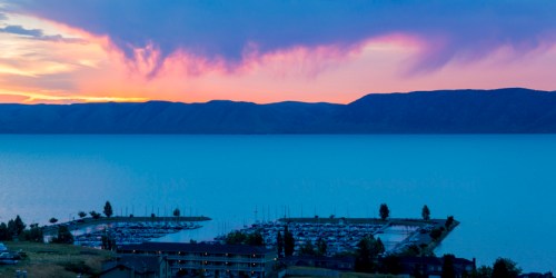 A serene lake at sunset, with colorful clouds reflecting over the water and a marina in the foreground.