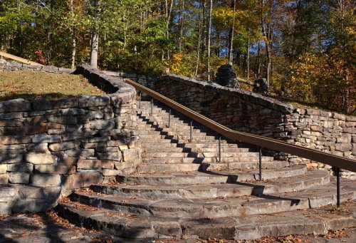 Winding stone staircase surrounded by trees and autumn foliage, leading up a hillside.
