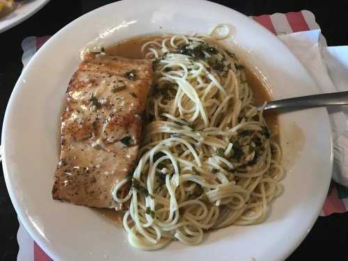 A plate of grilled salmon served with spaghetti tossed in a light herb sauce.