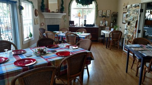Cozy dining area with checkered tablecloths, wooden chairs, and a fireplace, featuring a warm, inviting atmosphere.