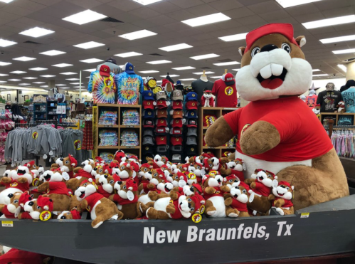 A display of large and small plush beavers wearing red hats at a store in New Braunfels, TX.