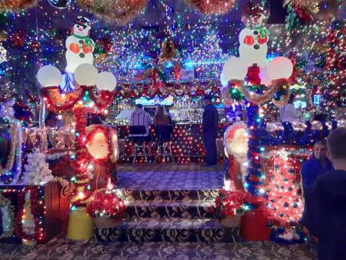 A festive bar decorated with colorful lights, snowmen, and Santa figures, creating a cheerful holiday atmosphere.