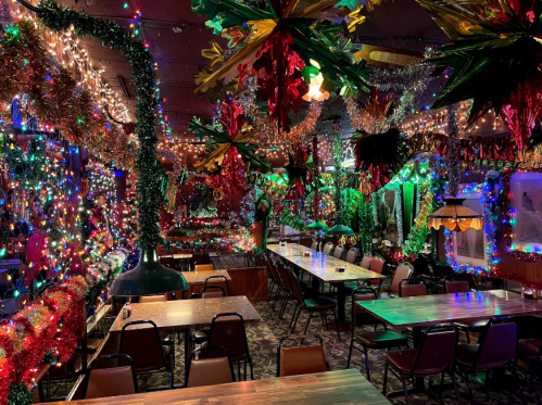 A vibrant restaurant interior adorned with colorful lights and festive decorations, featuring tables and chairs.