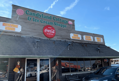 Exterior of Candyland Cottage & Ice Cream Shoppe, featuring a sign and open storefront with candy and ice cream offerings.