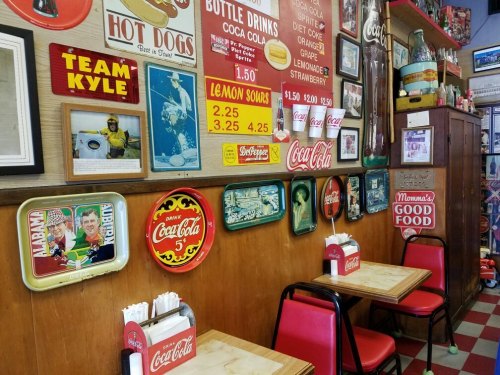A cozy diner interior with vintage signs, red chairs, and tables, featuring a nostalgic atmosphere and retro decor.