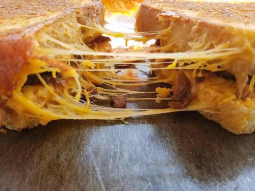 Close-up of a grilled cheese sandwich with gooey, melted cheese stretching between two golden-brown slices of bread.