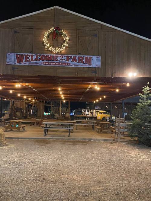 A rustic barn at night with a "Welcome to the Farm" sign, festive lights, and a Christmas wreath.