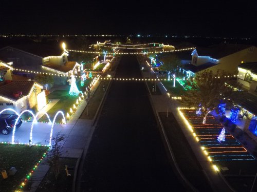 A festive neighborhood at night, adorned with colorful holiday lights and decorations along the streets and houses.