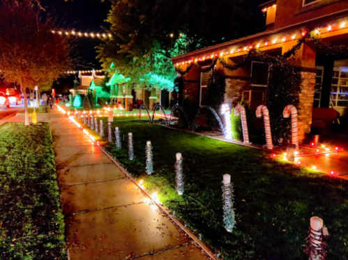 A festive street scene with houses decorated in colorful Christmas lights and candy cane lawn decorations.