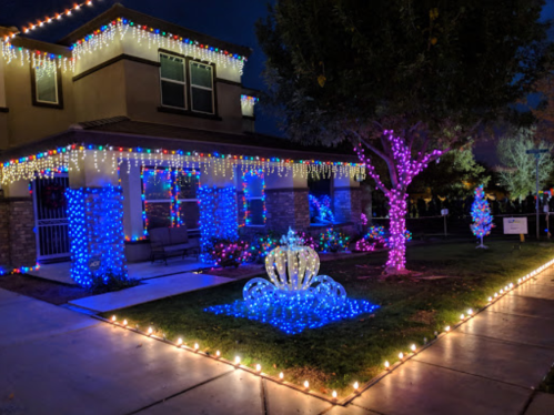 A beautifully decorated house at night, adorned with colorful lights and a glowing fountain in the front yard.