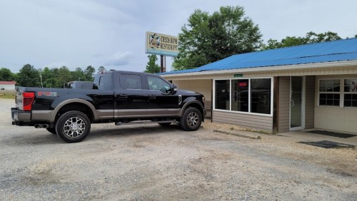 A black pickup truck parked outside a restaurant with a blue roof and a sign that reads "Cedar Bay Restaurant."