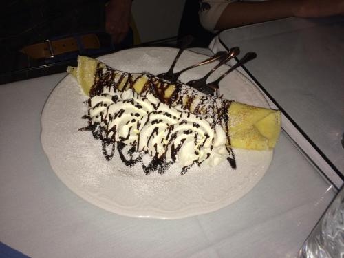 A dessert crepe filled with whipped cream and drizzled with chocolate sauce, served on a white plate.