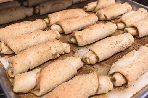 A tray of freshly baked cinnamon rolls coated in cinnamon sugar, arranged neatly on parchment paper.