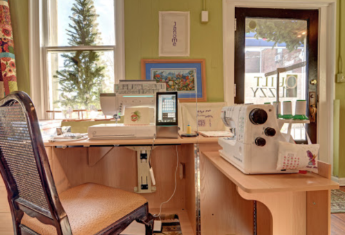 A cozy sewing workspace with a sewing machine, desk, and chair, featuring bright green walls and natural light.