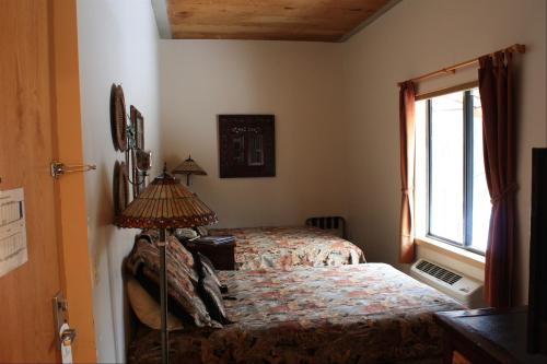 Cozy bedroom with two floral-patterned beds, a window, and decorative lamps. Warm, inviting atmosphere.