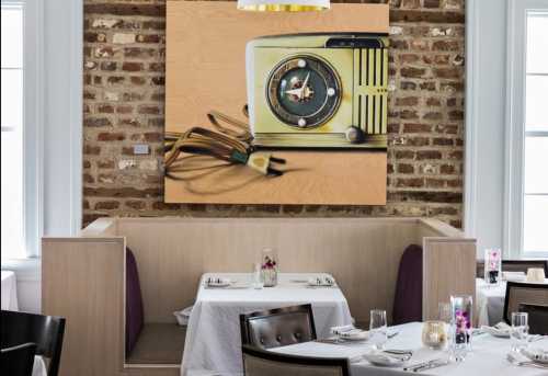 A cozy restaurant interior featuring a wooden booth and a vintage radio artwork on a brick wall.