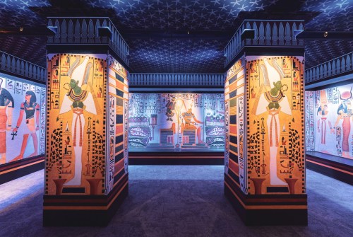 A vibrant exhibition space featuring ancient Egyptian murals and columns adorned with colorful hieroglyphics.