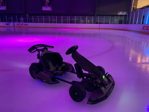 A sleek go-kart designed for ice, illuminated by purple lights on a rink.