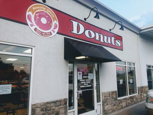 Exterior of a donut shop with a large sign reading "Donuts" and an open door, showcasing a welcoming atmosphere.