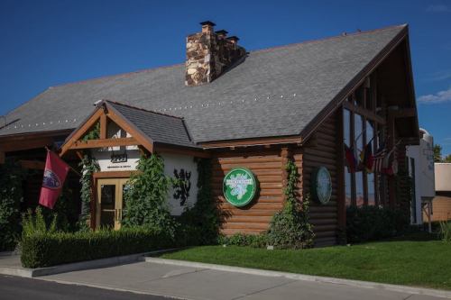 A rustic building with a stone chimney, surrounded by greenery and flags, under a clear blue sky.