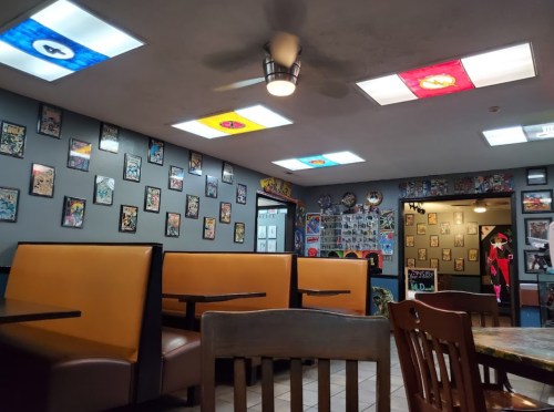 Interior of a colorful restaurant with booth seating, vibrant ceiling lights, and walls adorned with framed artwork.