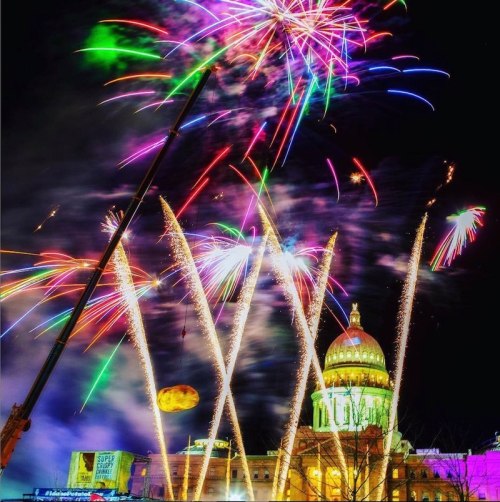 Colorful fireworks burst over a grand dome building at night, illuminating the sky with vibrant lights.