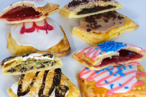 A variety of colorful pastries with different fillings and toppings, including icing, sprinkles, and chocolate drizzle.