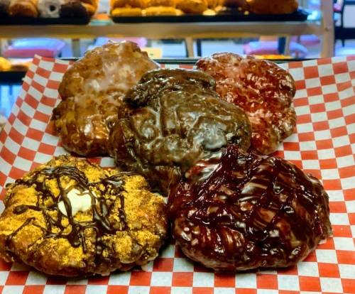 A variety of colorful, glazed donuts arranged on a red and white checkered paper.