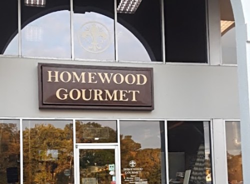 Sign for "Homewood Gourmet" displayed on a storefront with large windows and a modern design.