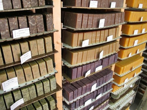 Shelves filled with various bars of soap in different colors and textures, labeled with product names.