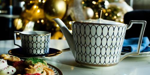 A decorative teapot and cup on a table, with festive cookies and a blurred Christmas tree in the background.