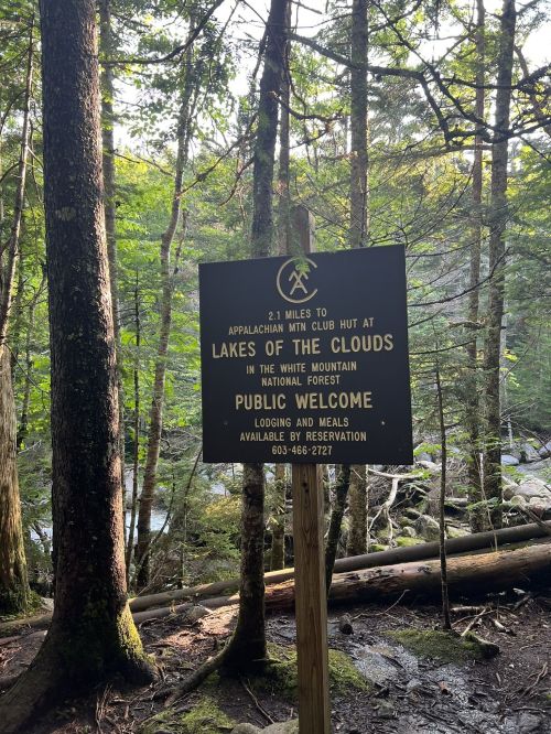 Sign indicating 2.1 miles to Lakes of the Clouds Hut in the White Mountain National Forest, with details on lodging and meals.