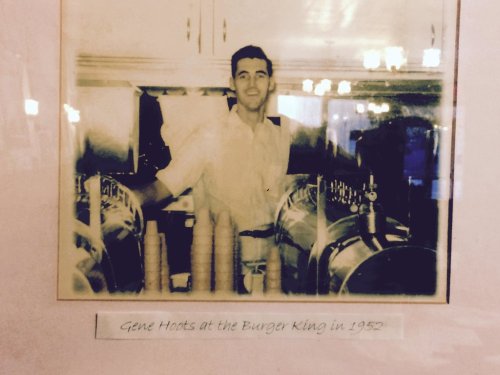 Black and white photo of a man standing behind a counter at Burger King in 1952, with ice cream machines in view.