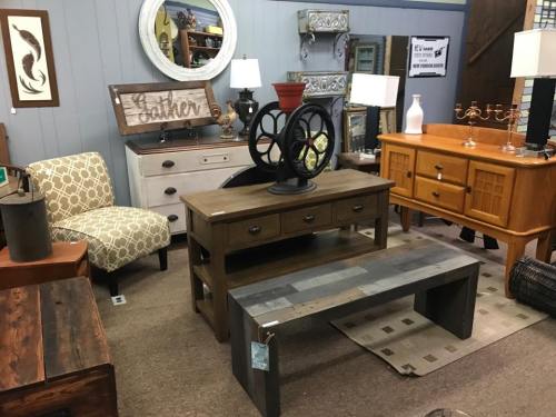 A cozy furniture store display featuring various tables, chairs, and decorative items in a warm, inviting setting.