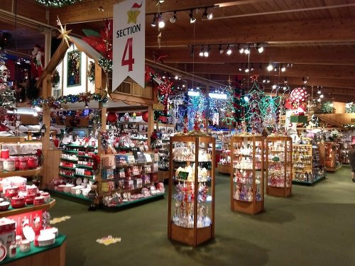 A festive store interior filled with holiday decorations, displays, and colorful lights, showcasing various seasonal items.