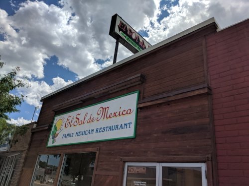 Sign for "El Sol de Mexico" Family Mexican Restaurant on a building under a cloudy sky.