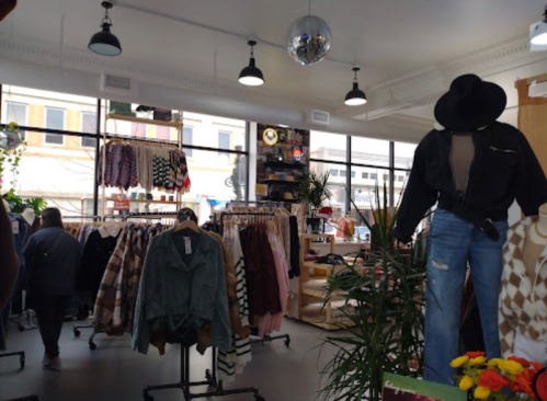 A trendy clothing store interior with racks of apparel, a disco ball, and a mannequin dressed in casual fashion.