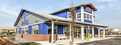 A modern blue and brick restaurant building with large windows and a welcoming entrance.