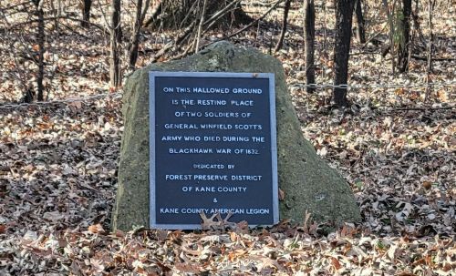 A stone marker in a wooded area commemorating two soldiers from the Black Hawk War, dedicated by local organizations.