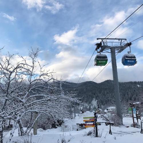 A snowy landscape with a cable car system and mountains in the background under a blue sky with clouds.