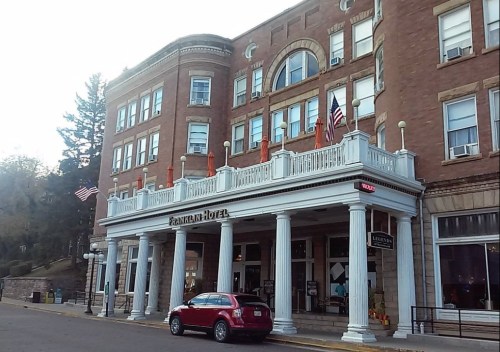 Historic hotel with a grand entrance, featuring columns and flags, set in a scenic location.
