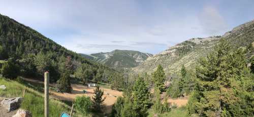 A panoramic view of a lush green valley surrounded by mountains under a clear sky.