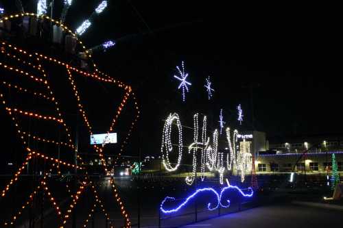 Colorful holiday lights display at night, featuring the words "O Holy Night" and decorative stars.